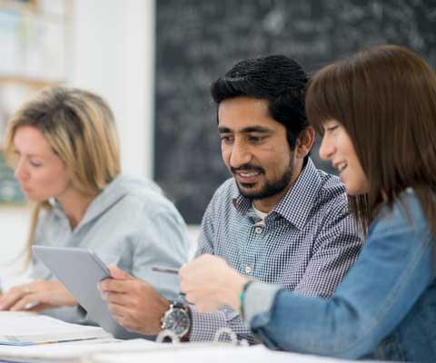 Des jeunes professionnels travaillent et regardent à une tablette.