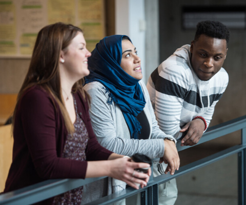 Three students leaning on a ledge