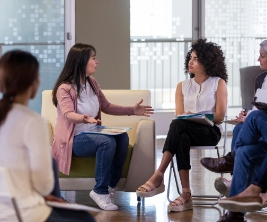 Un groupe de personnes assises dans un cercle ayant une discussion animée.