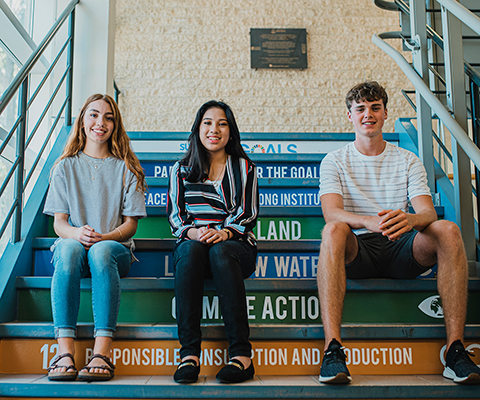 Students sitting on steps in the front of camera 