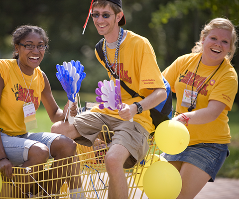 3 students wearing yellow tea shirt and Laughing