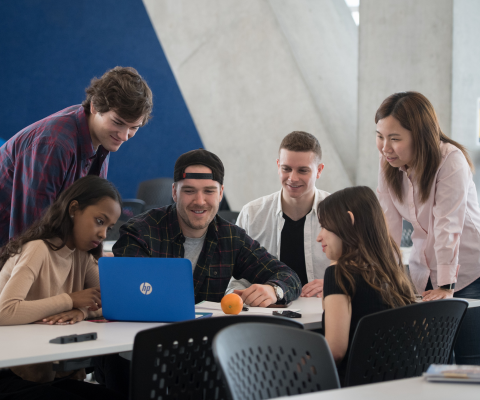 A group of six diverse students around a laptop / Un groupe de six étudiants divers autour d’un ordinateur portable