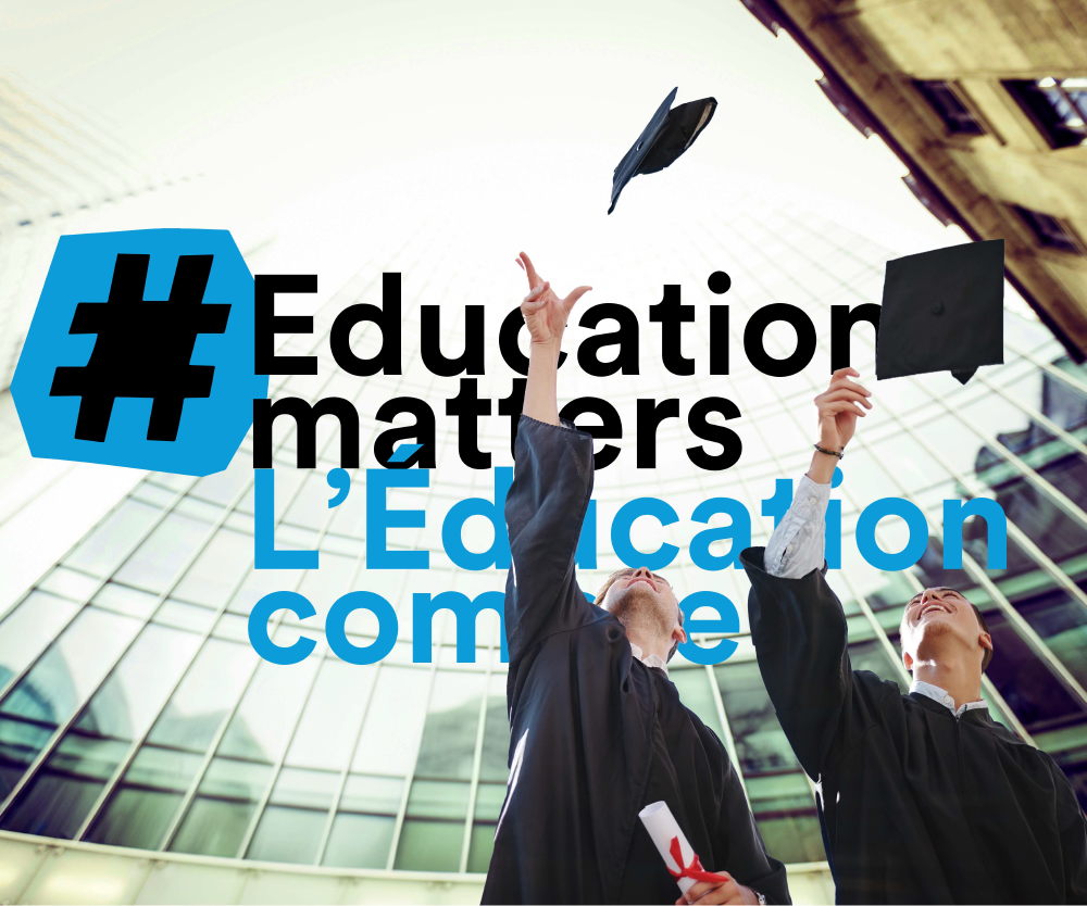 Graduates throw cap in front of skyscrapers